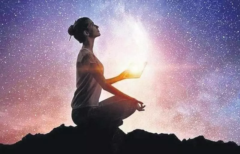 magem de uma pessoa meditando ao pôr do sol, simbolizando a espiritualidade no ser humano, conexão interior e equilíbrio emocional.
