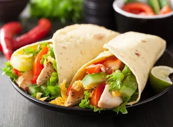 Wraps de alface com frango desfiado recheados com cenoura ralada, pepino em tiras e avocado, servidos em um prato branco como opção leve e saudável para refeições fitness.